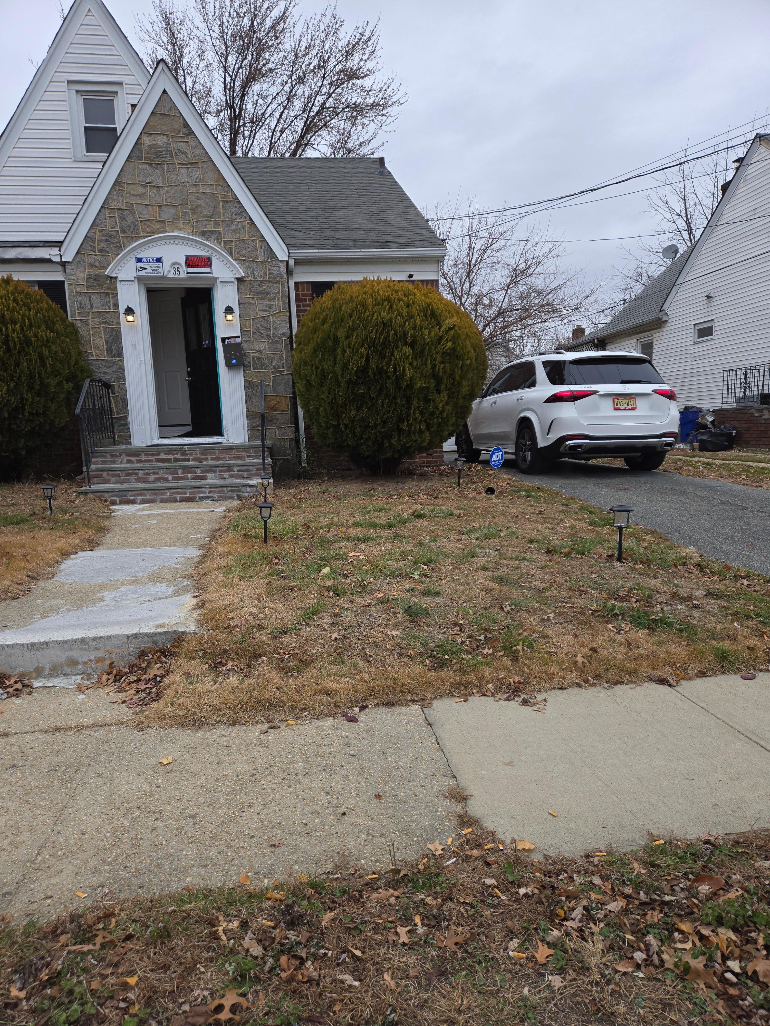 Exterior of home,  full of leaves and debris: water bottles, cigarette butts, etc