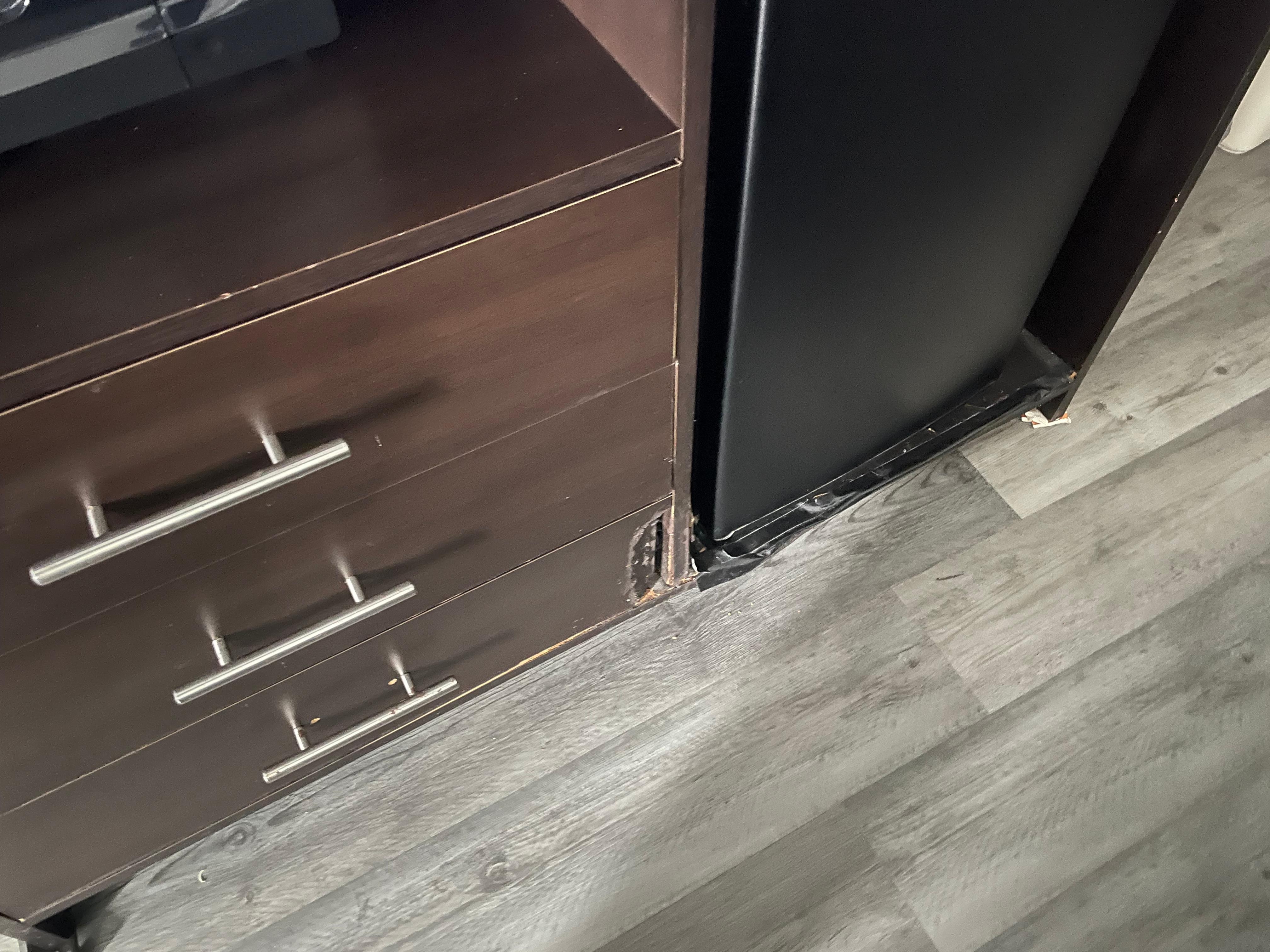 Broken tv stand, they used a door stopper on the left and some kind of food container on the right. Tape to cover or maybe help secure the from damage. 