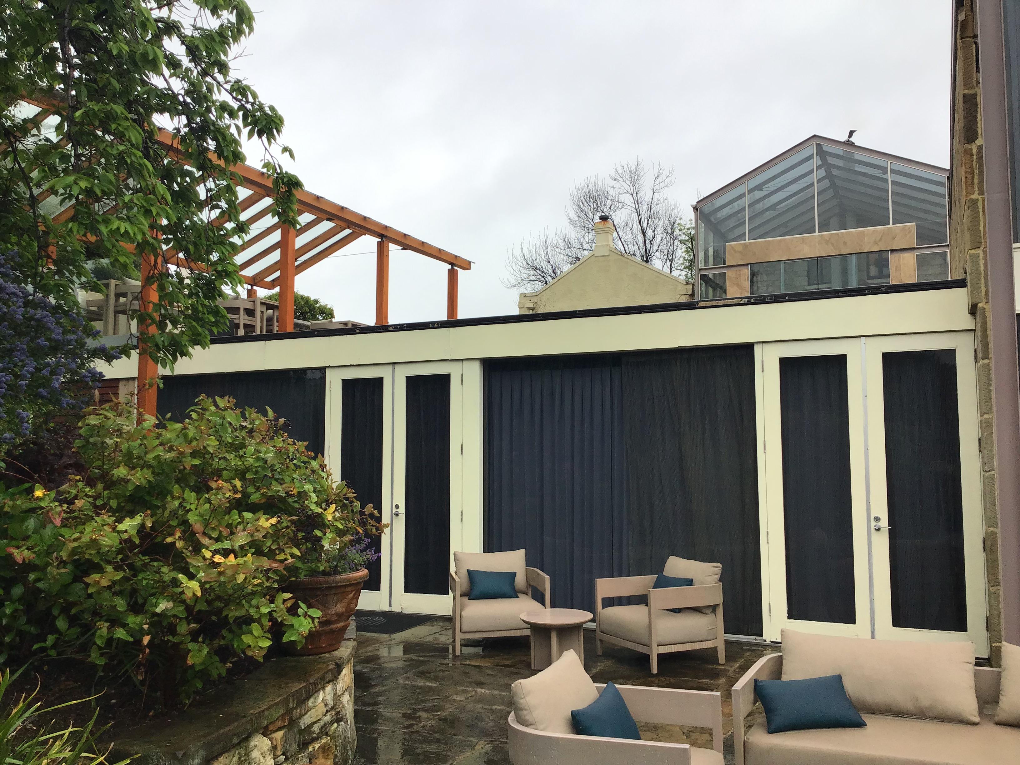 Outdoor view of a lower floor room with covered outdoor area above.