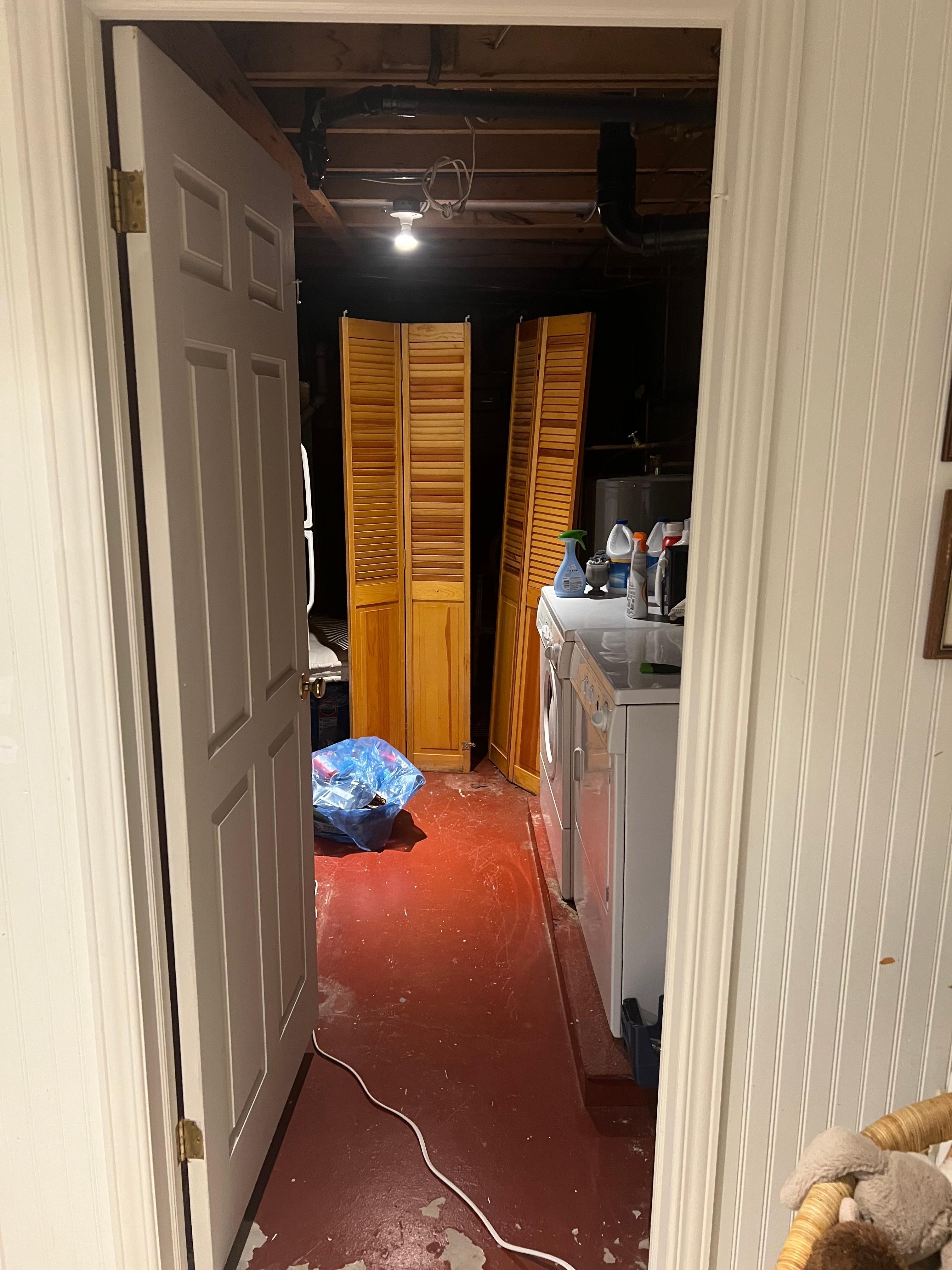 Laundry room in basement, complete with bag of old recycling.