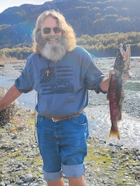 I stopped at a scenic area near the highway and got out of my car to take pictures. I noticed salmon running in the stream and decided to roll up my pant legs and shirt sleeve and enter the stream after one. This picture resulted.
