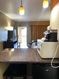 Microwave, frig, coffeemaker, countertop, two tall chairs