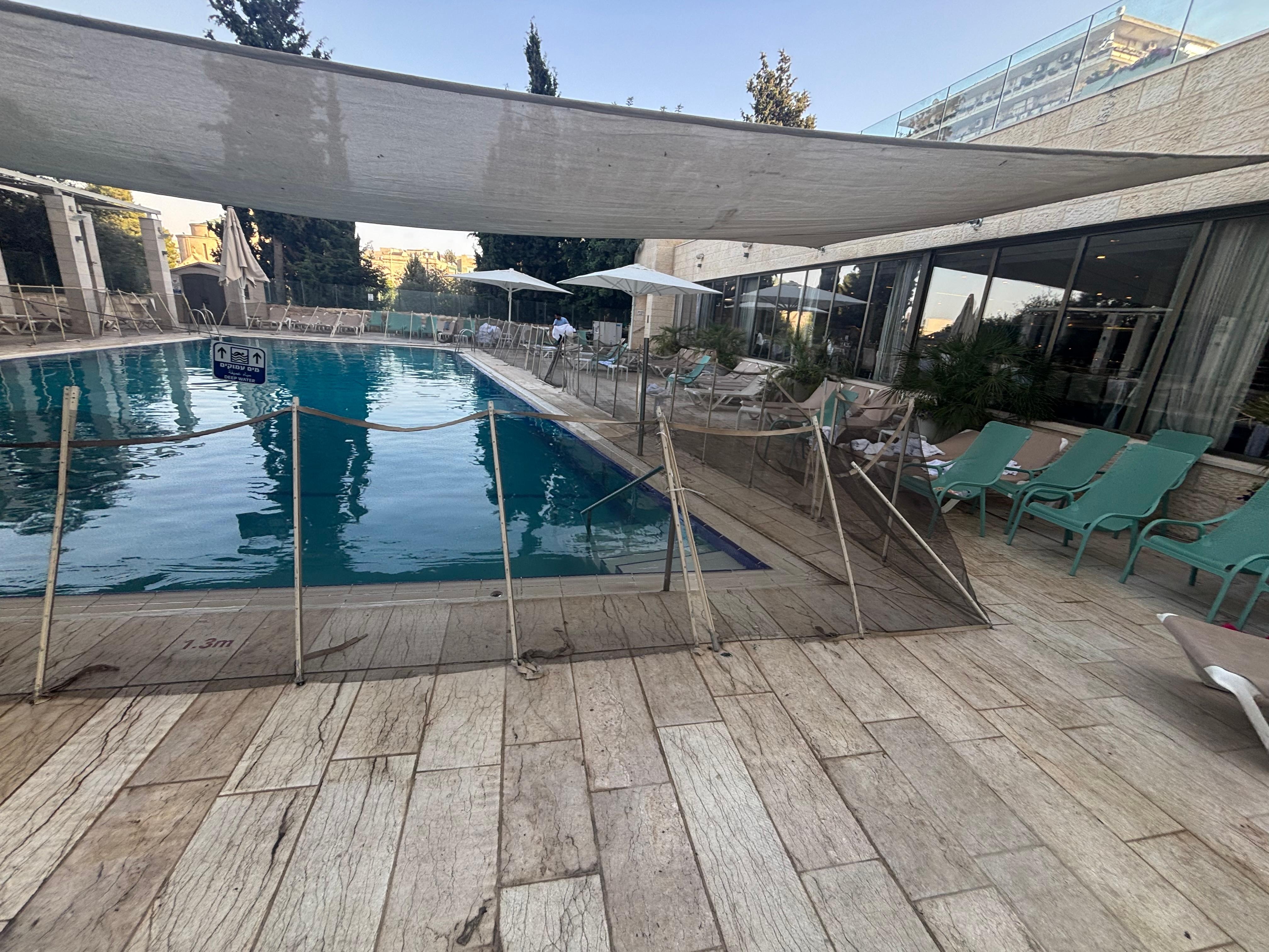 A sad excuse for a hotel pool — surrounded by a ragged rope fence like a crime scene, filthy tiles, and broken loungers. Nothing inviting here, unless you’re a fan of disappointment