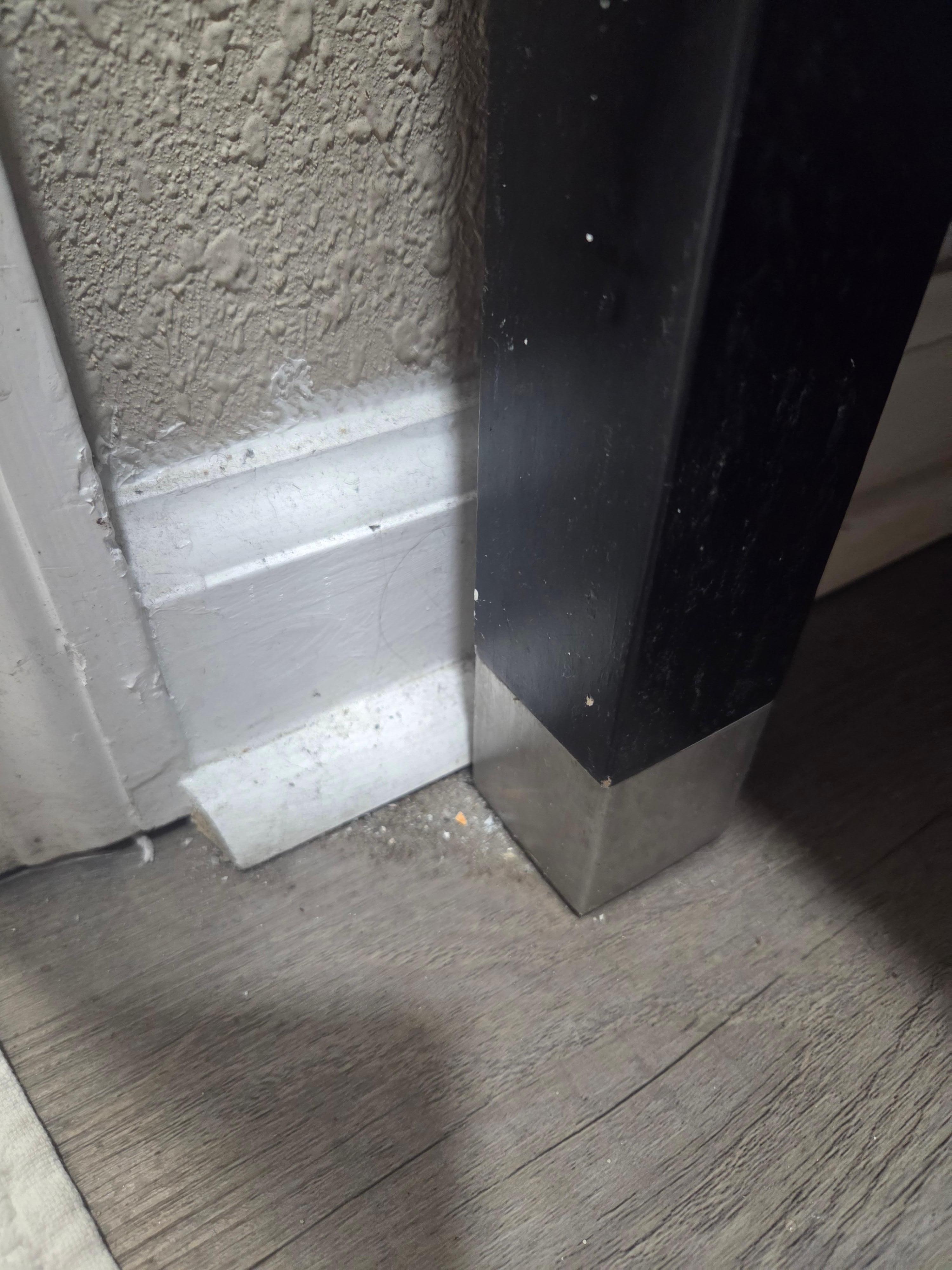 Dirt in the corners of the floor and trim.