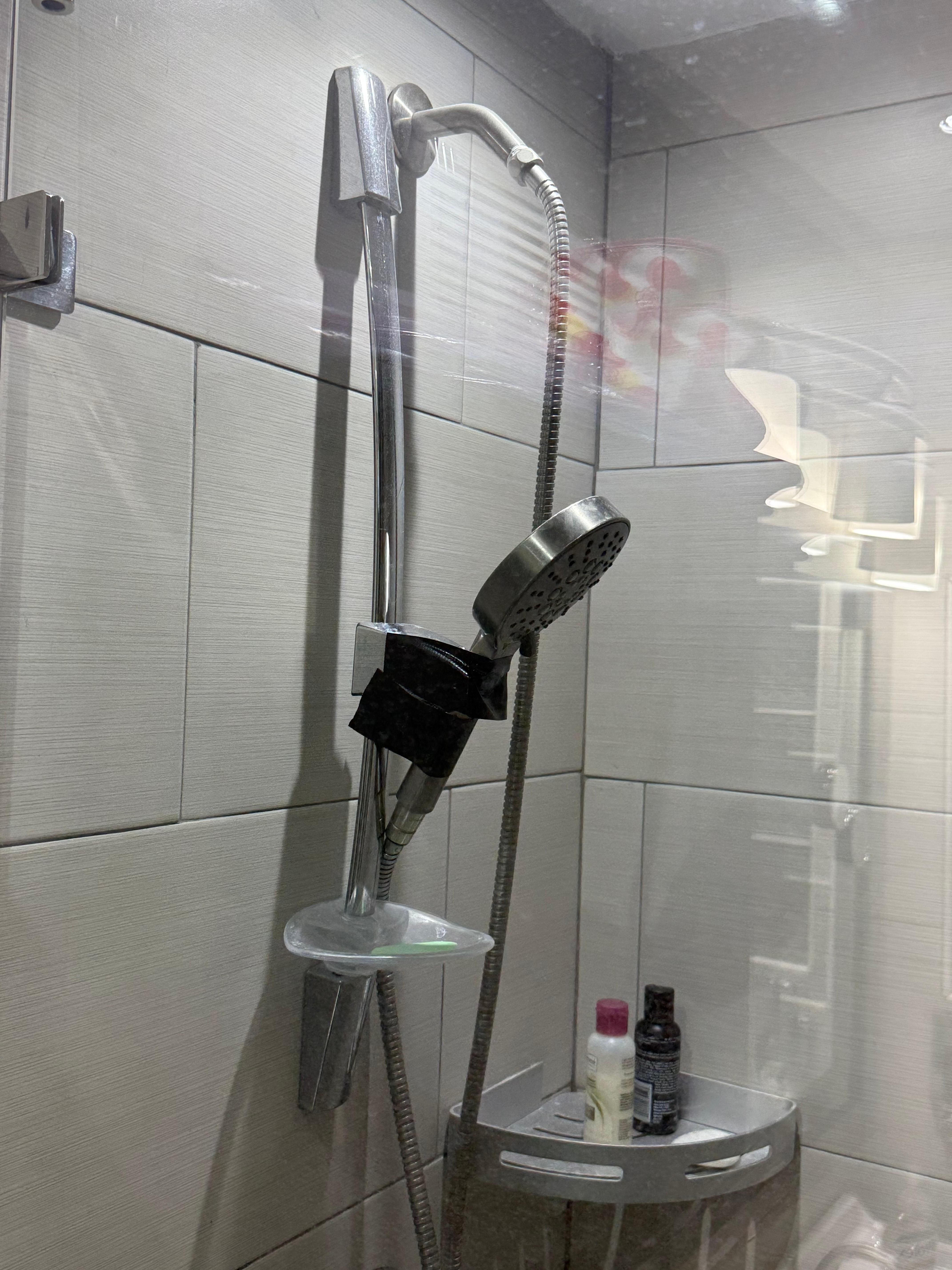Shower head in queen bathroom held up with duct tape. 