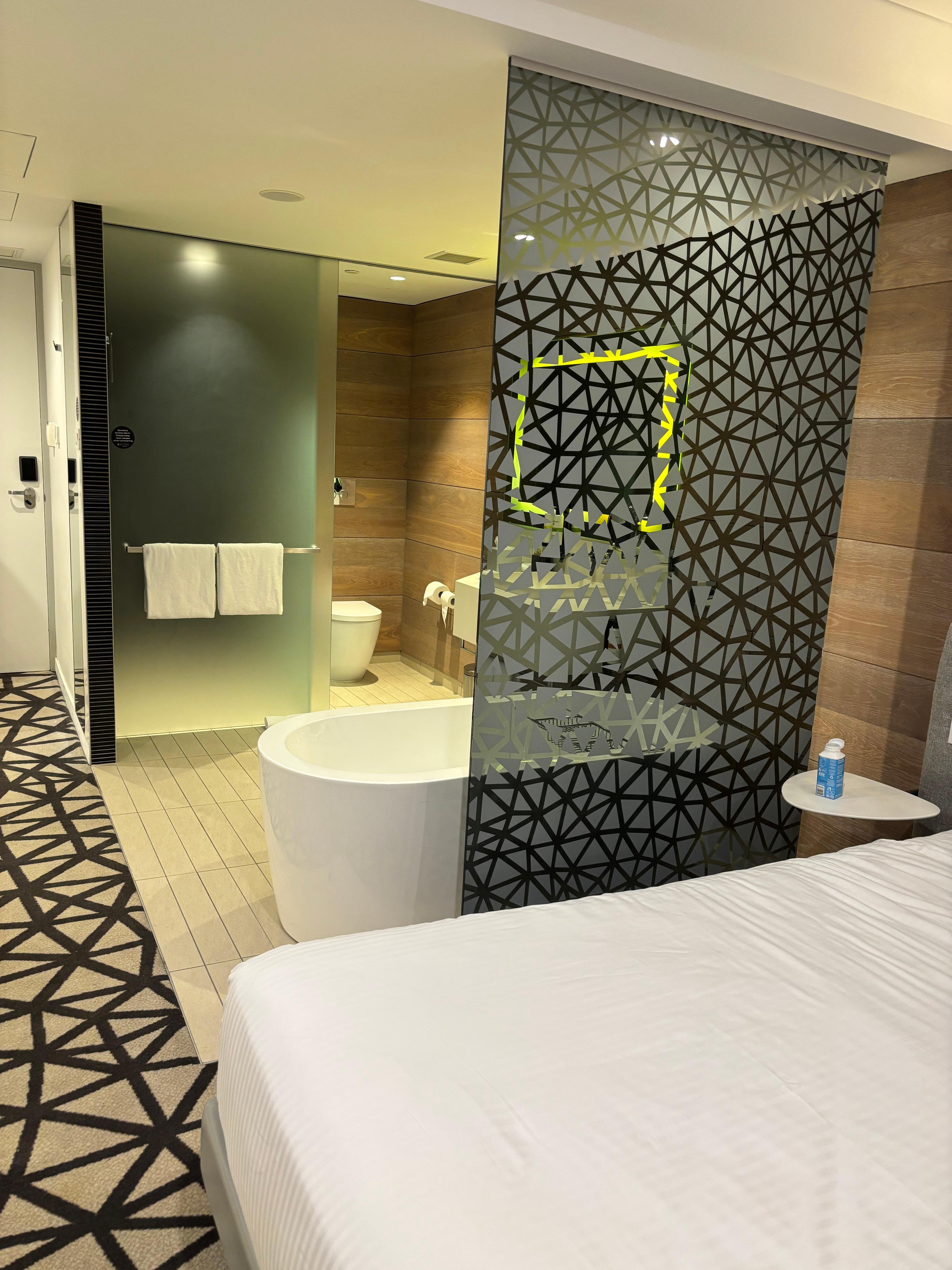 仕切りも無く部屋の中央にあるバスタブ。トイレとシャワーのドアはガラスの引き戸。一方を閉めると一方が開く。