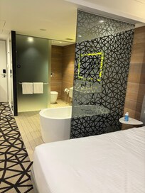 仕切りも無く部屋の中央にあるバスタブ。トイレとシャワーのドアはガラスの引き戸。一方を閉めると一方が開く。