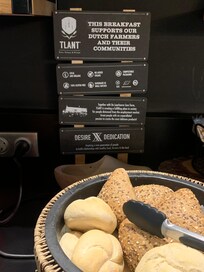 Sign including 100% gluten free behind basket of bread rolls