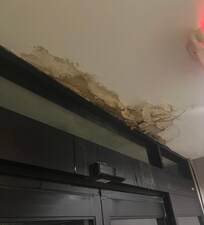 Ceiling damaged and falling on floor at back entrance near elevator