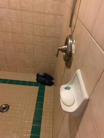 Used bandage and shower shoes in shower stall.