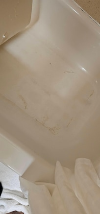 shower mat with gunk built up underneath and on tub
