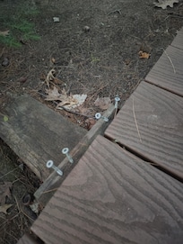 Nails sticking up from wood down by water where the chairs, table and fire pit are.