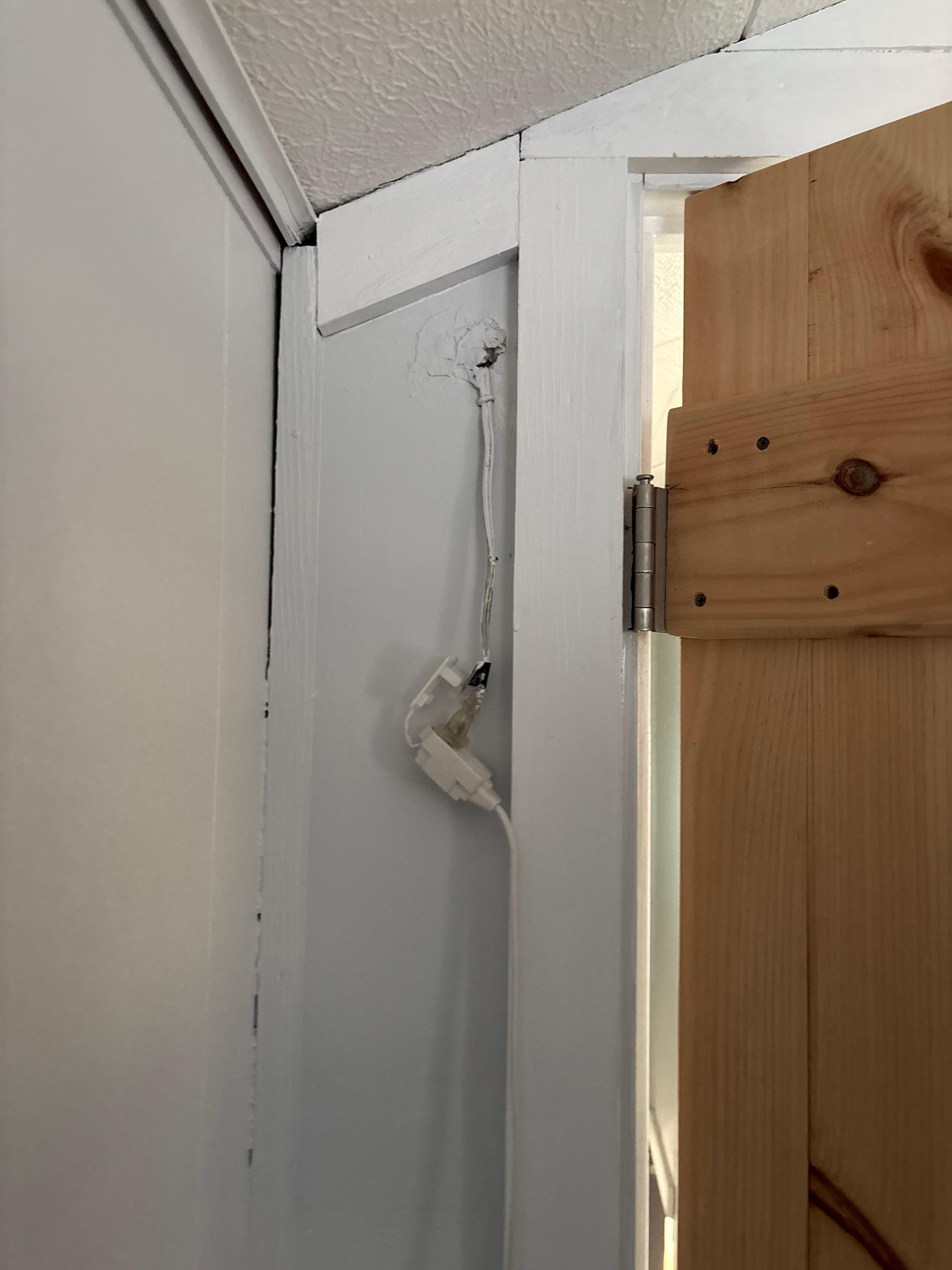 Bedroom extension chords hanging from inside wall 