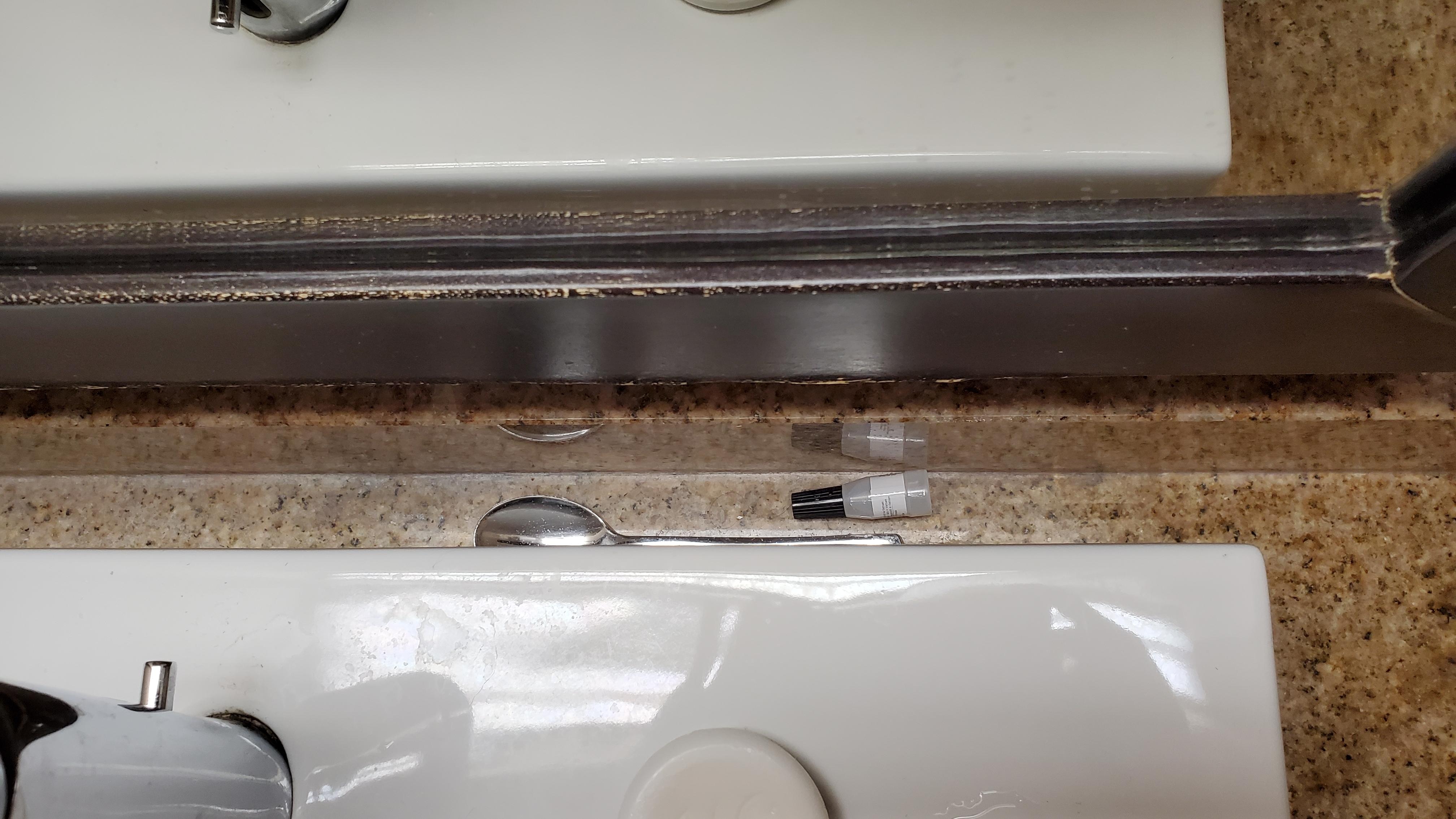 I think the small bottle is full of white powder but too disgusted to look closer, spoon next to it behind the sink and mirror. 