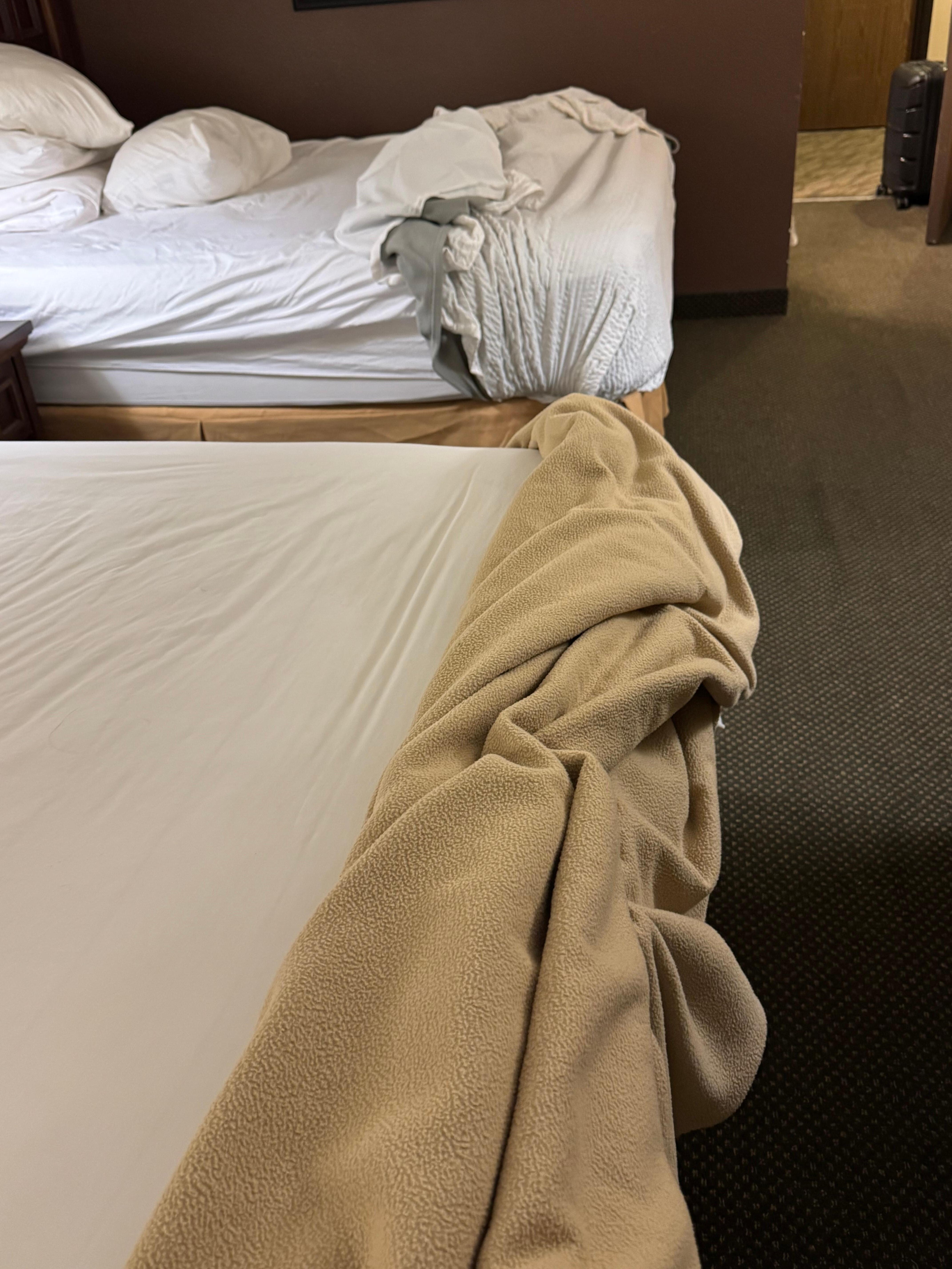 This bed on the left is missing its sheet. The far away bed is fine
