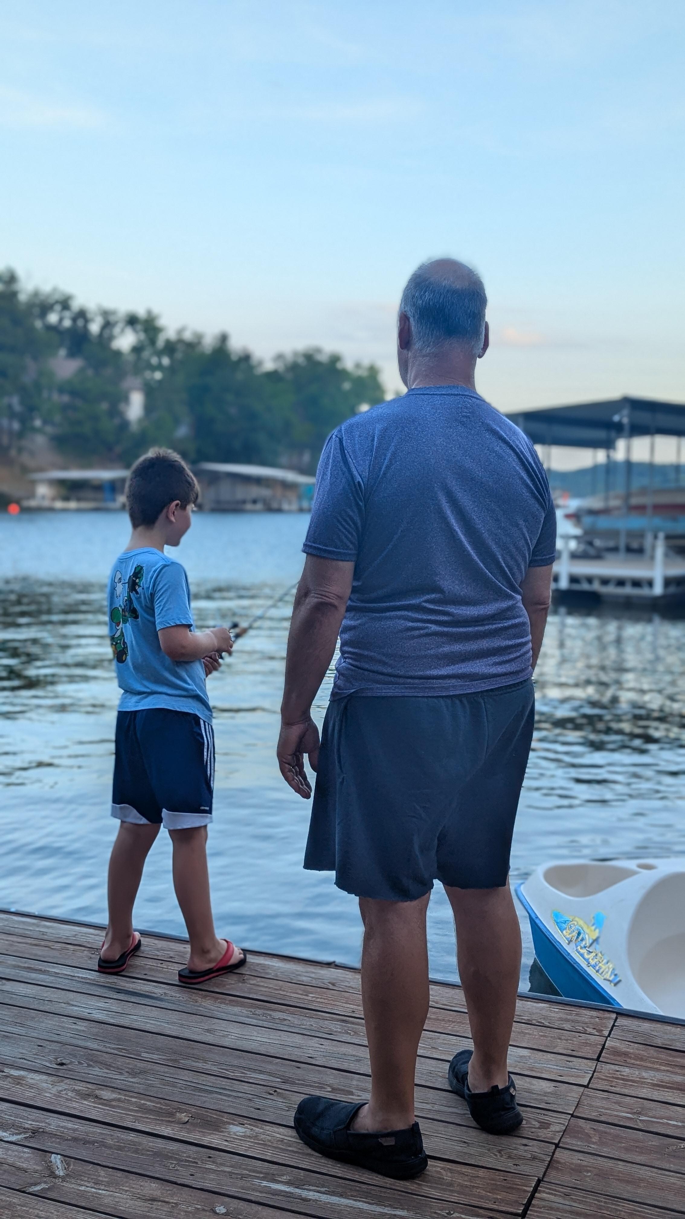 Grandpa and grandson casting a line from the dock.