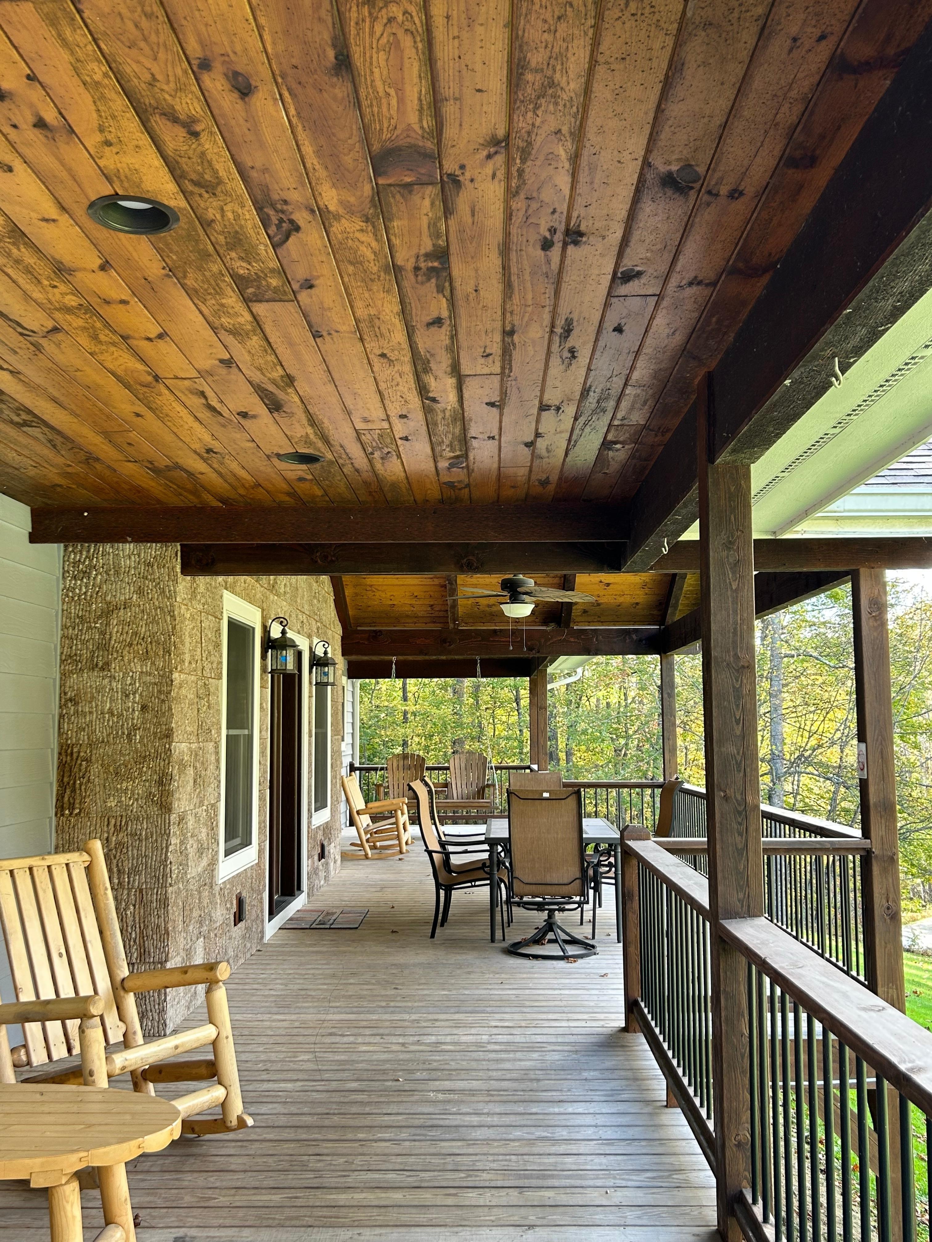 Huge front porch with outdoor dining table & chairs and a porch swing