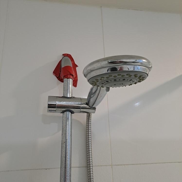 Shower head held against the wall by tape