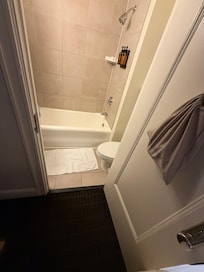 View of bathroom door touching bed and desk