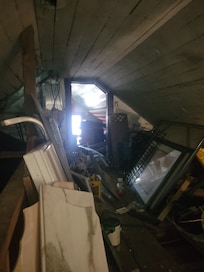 Junk piled up, and the window on the end of the hall is missing.