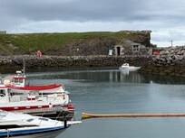 Fisherman returning to the harbour with the Giantess cave in background, cute little thing to visit while there.