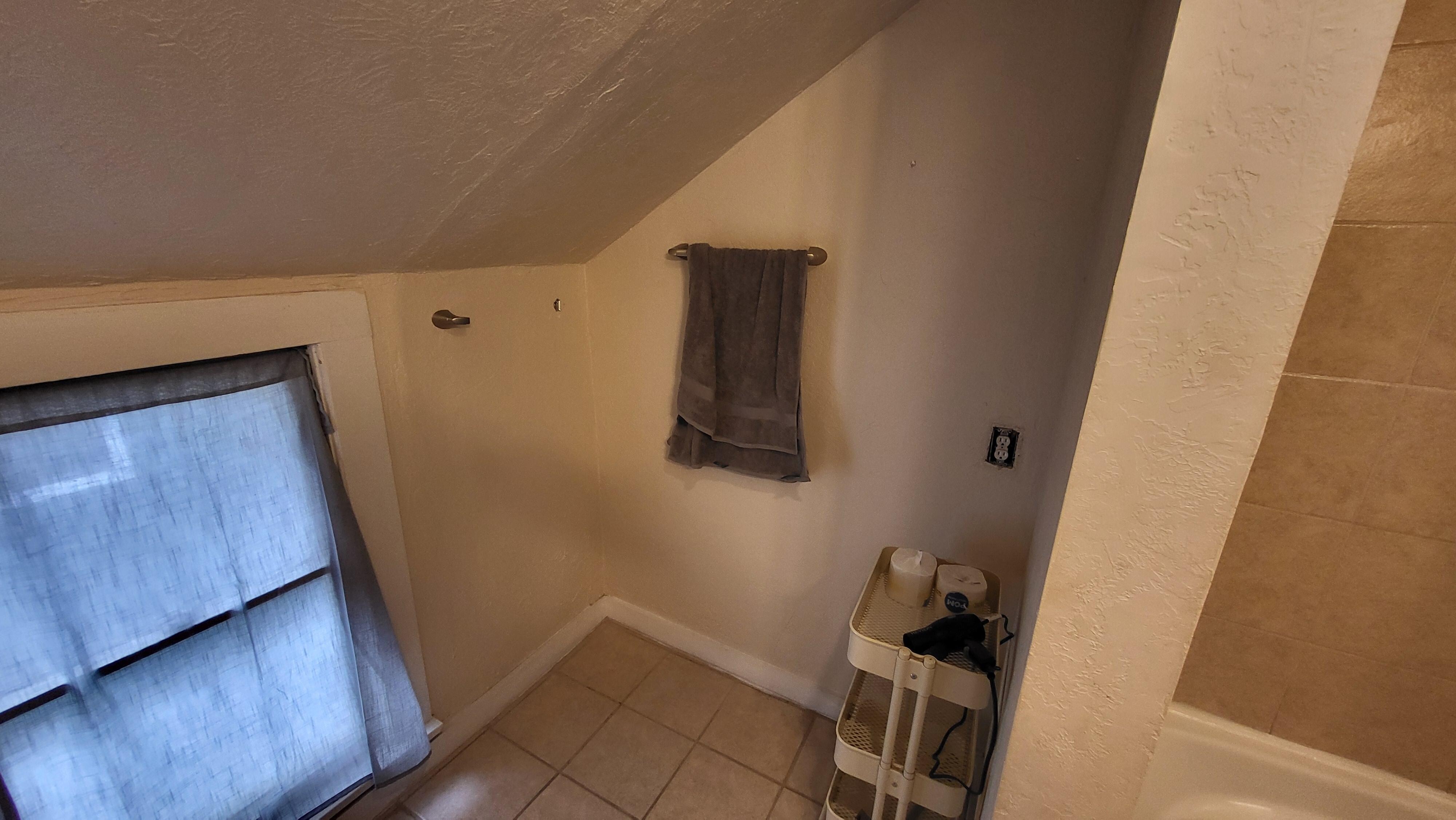 Upstairs bathroom with missing towel rack and uncovered electrical outlet
