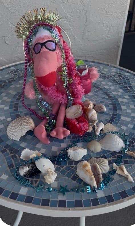 My traveling Flamingo!! Decorated for New Year’s Eve, surrounded by sea shells collected by walks on the beautiful beach. 