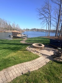 Updated view of the fire pit and gorgeous yard overlooking the lake and dock.