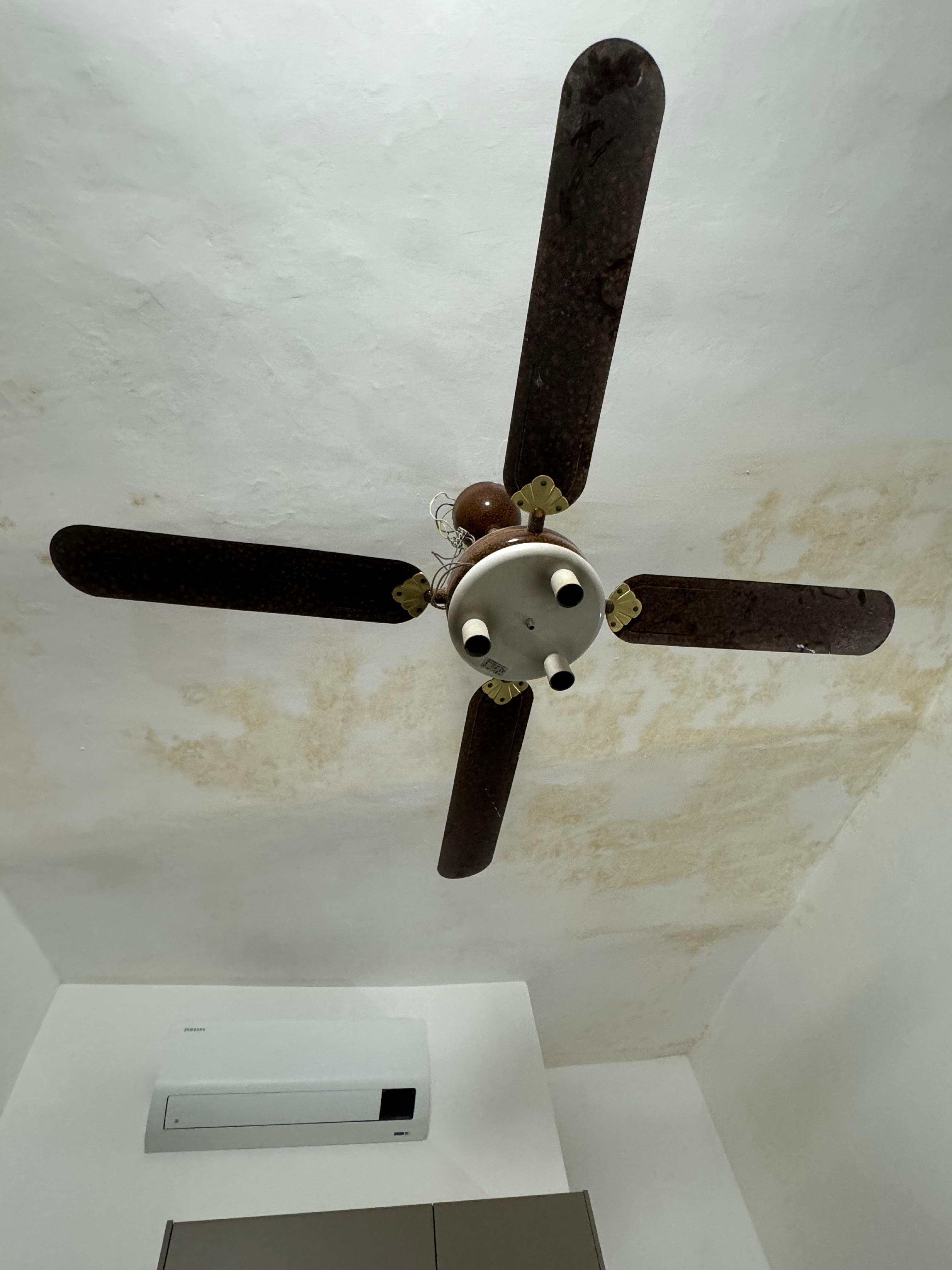 Broken, dirty old fan and stained ceiling 