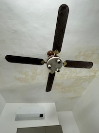 Broken, dirty old fan and stained ceiling