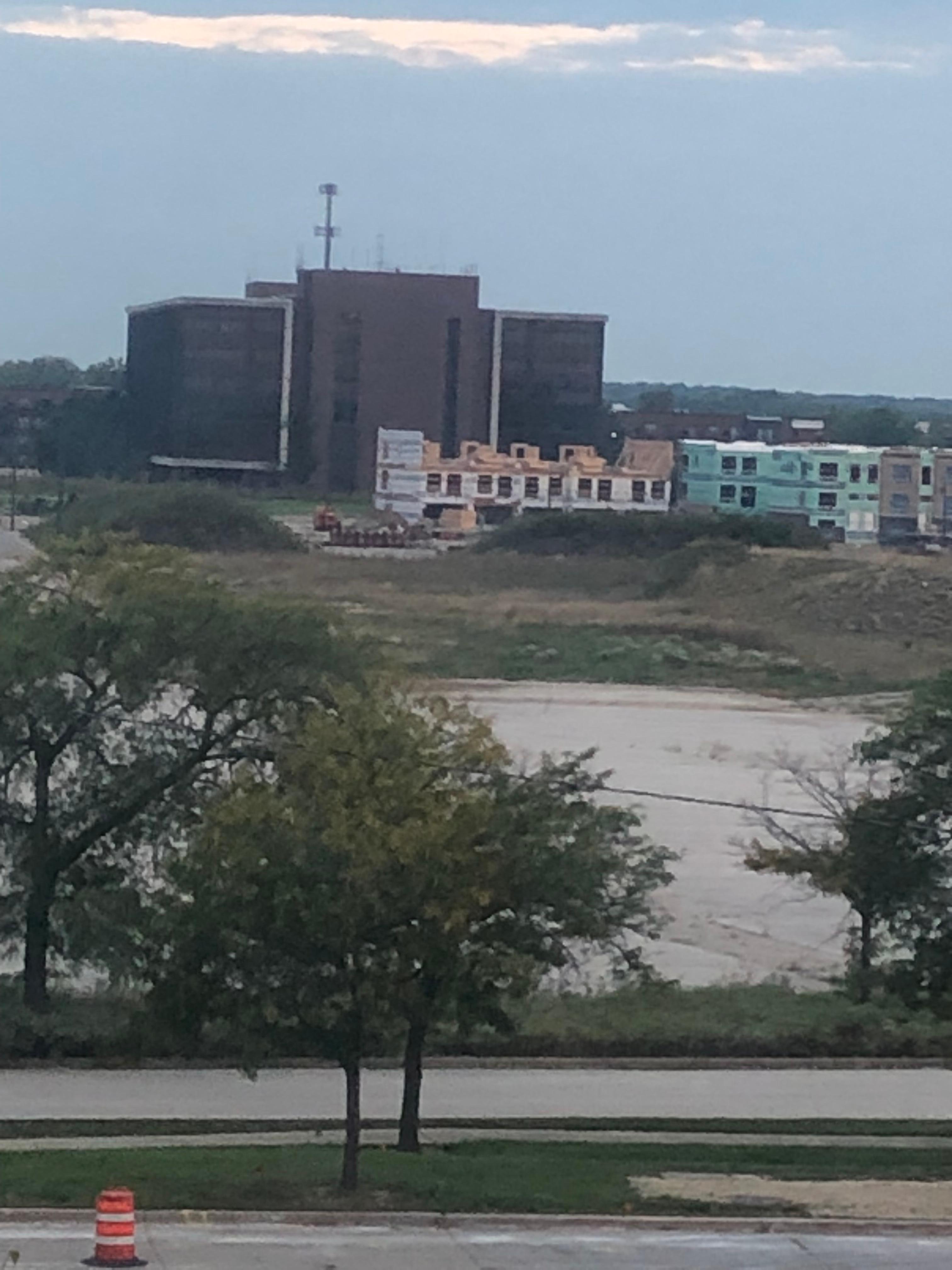 Un beau bloc blanc ayant en arrière-plan une grande bâtisse en briques cuites.