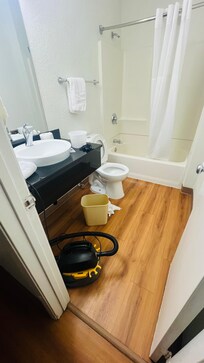 Un baño sucio un baño sin regadera un excusado tapado y una aspiradora dentro del baño