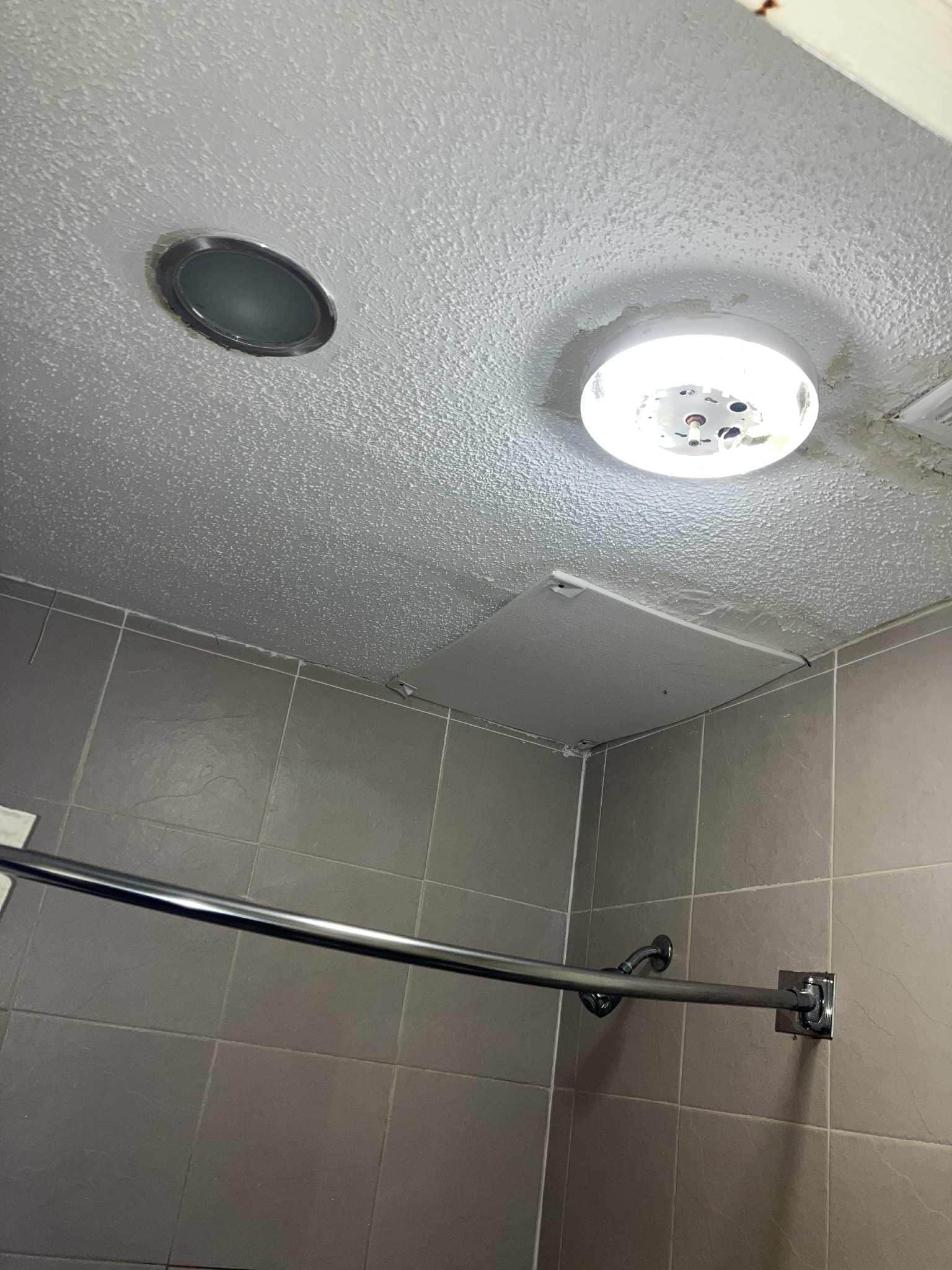 Bathroom light fixture broken and exposed light. Mold on ceiling.