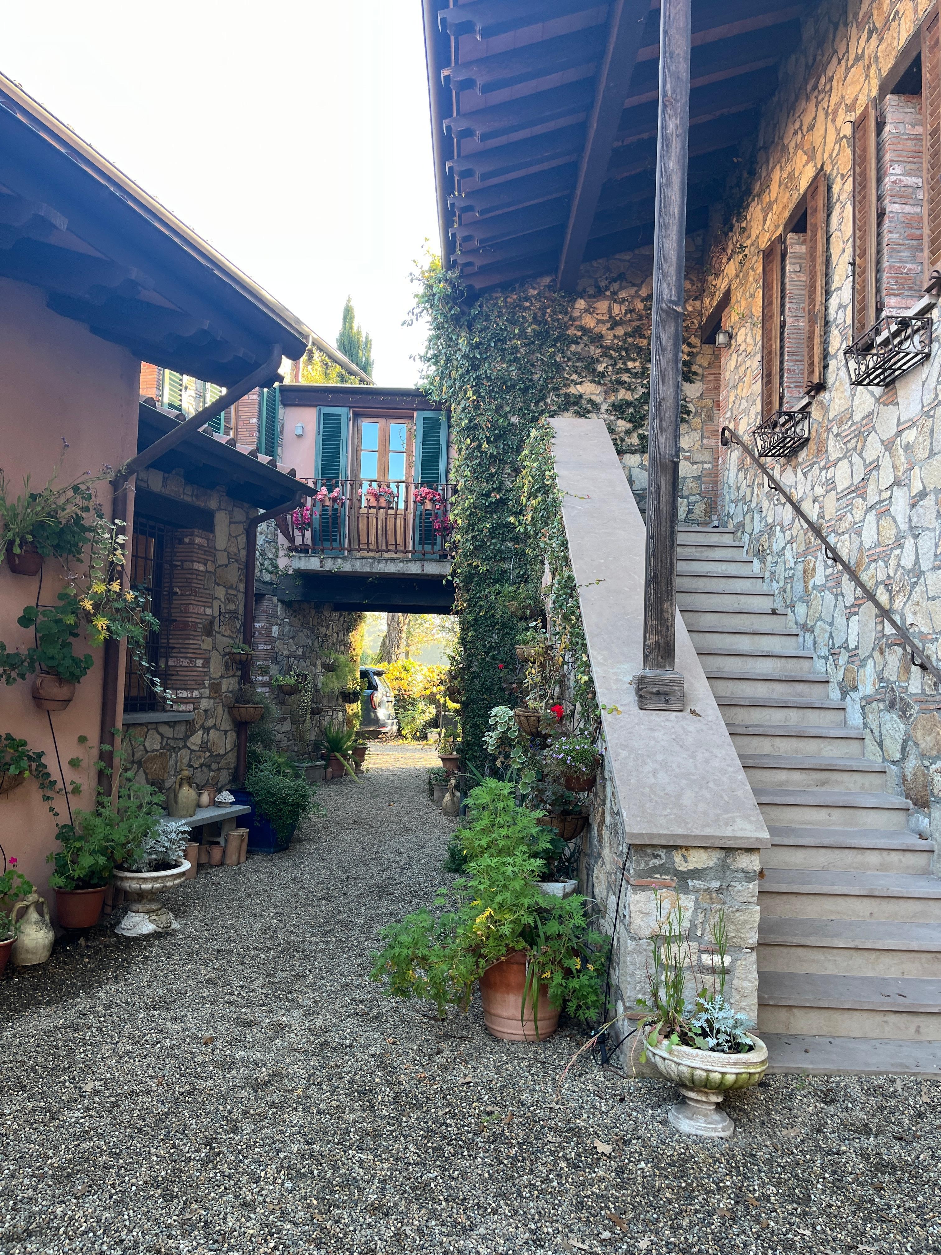 Alley between garage and main house with stairs and upper walkway to Lucca room