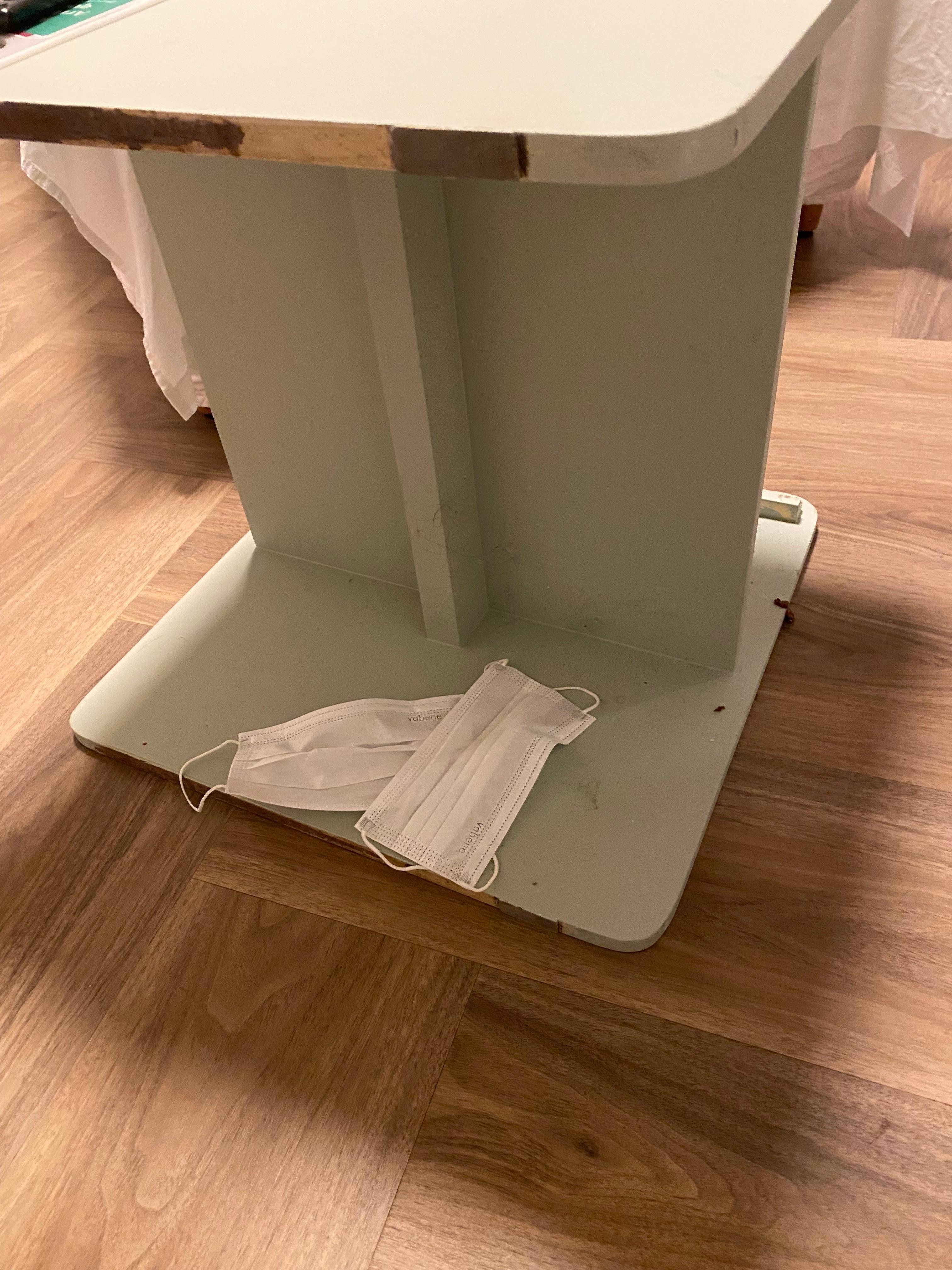 Mesa de cabeceira que tava encostada na parede, máscaras usadas, resto de bolacha e muita sujeira.