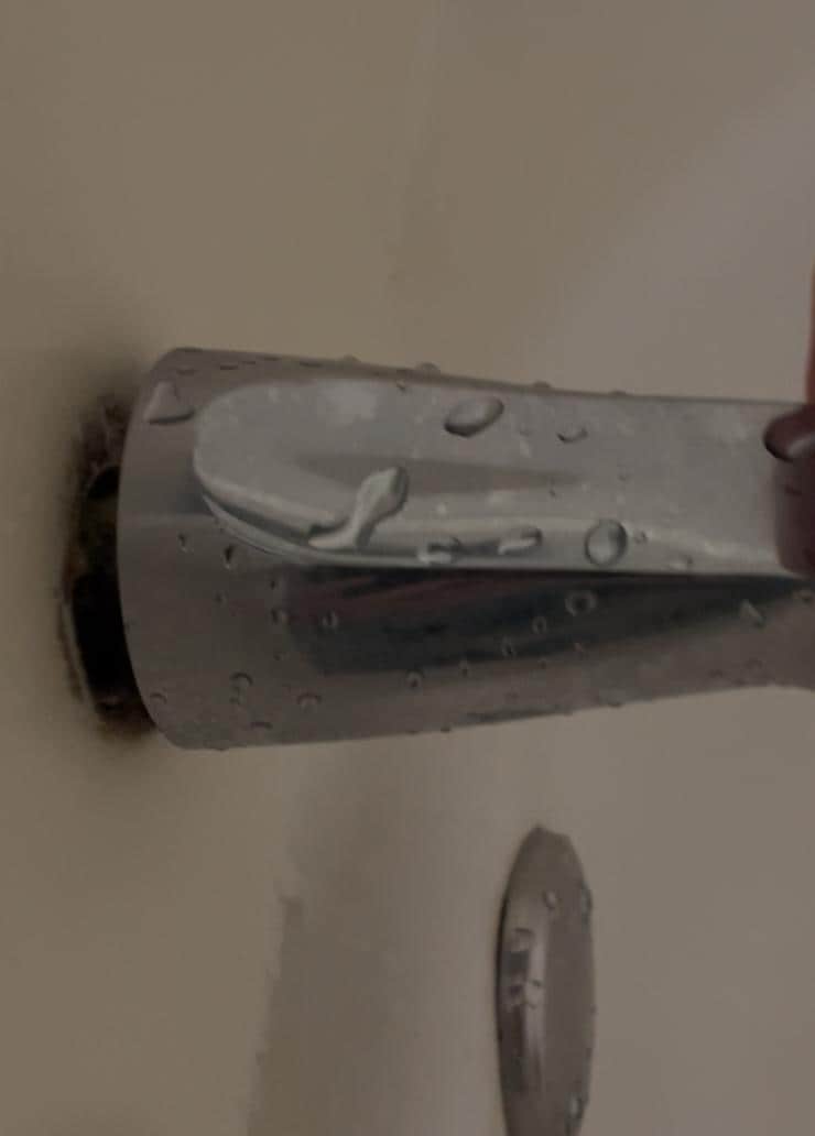 The faucet was not attached to the tub, so you had to hold it still with one hand while you pulled the button up to turn the shower on. 