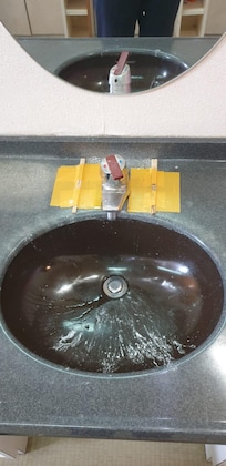 Heavily stained and damaged wash basin and tap faucet