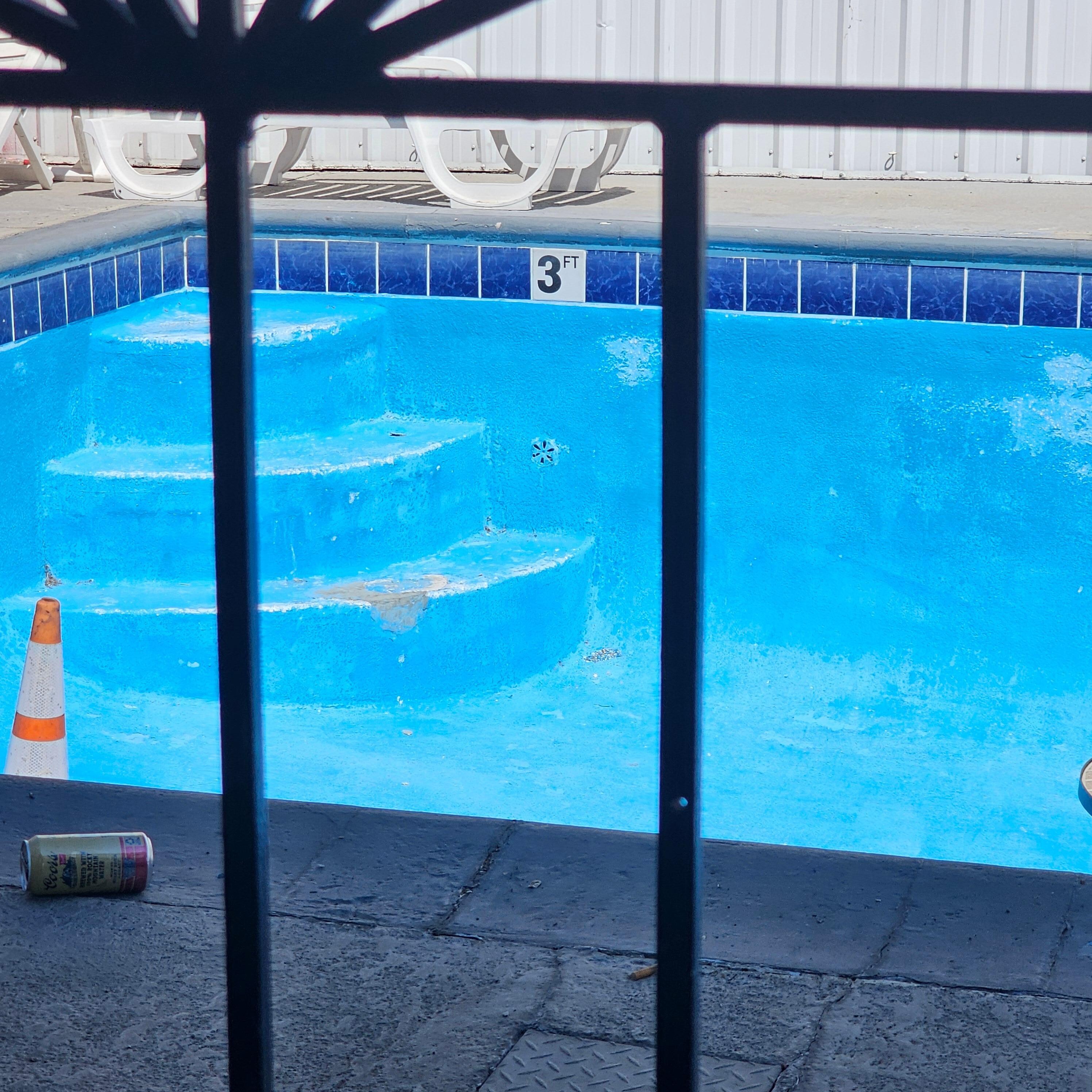 Broken empty pool with beer can and traffic cone