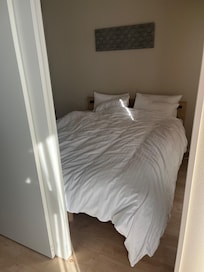 One of the bedrooms across from the kitchen with a queen bed and closet. The doors are on tracks so you can have them opened or closed