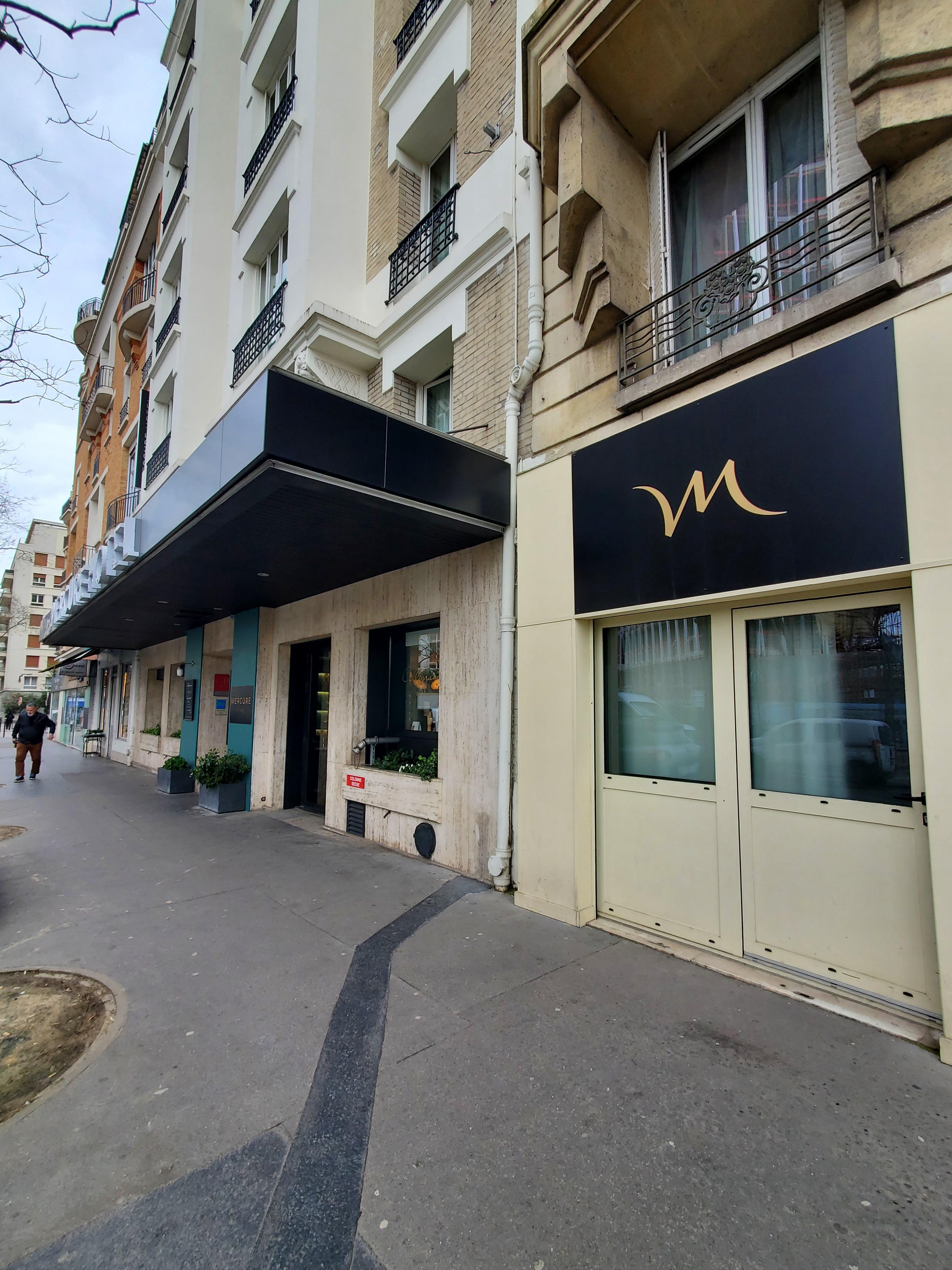 Front of the hotel with the apartment entrance being separate with the "M" above the unit on the ground floor