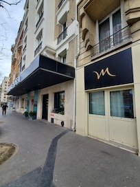Front of the hotel with the apartment entrance being separate with the "M" above the unit on the ground floor