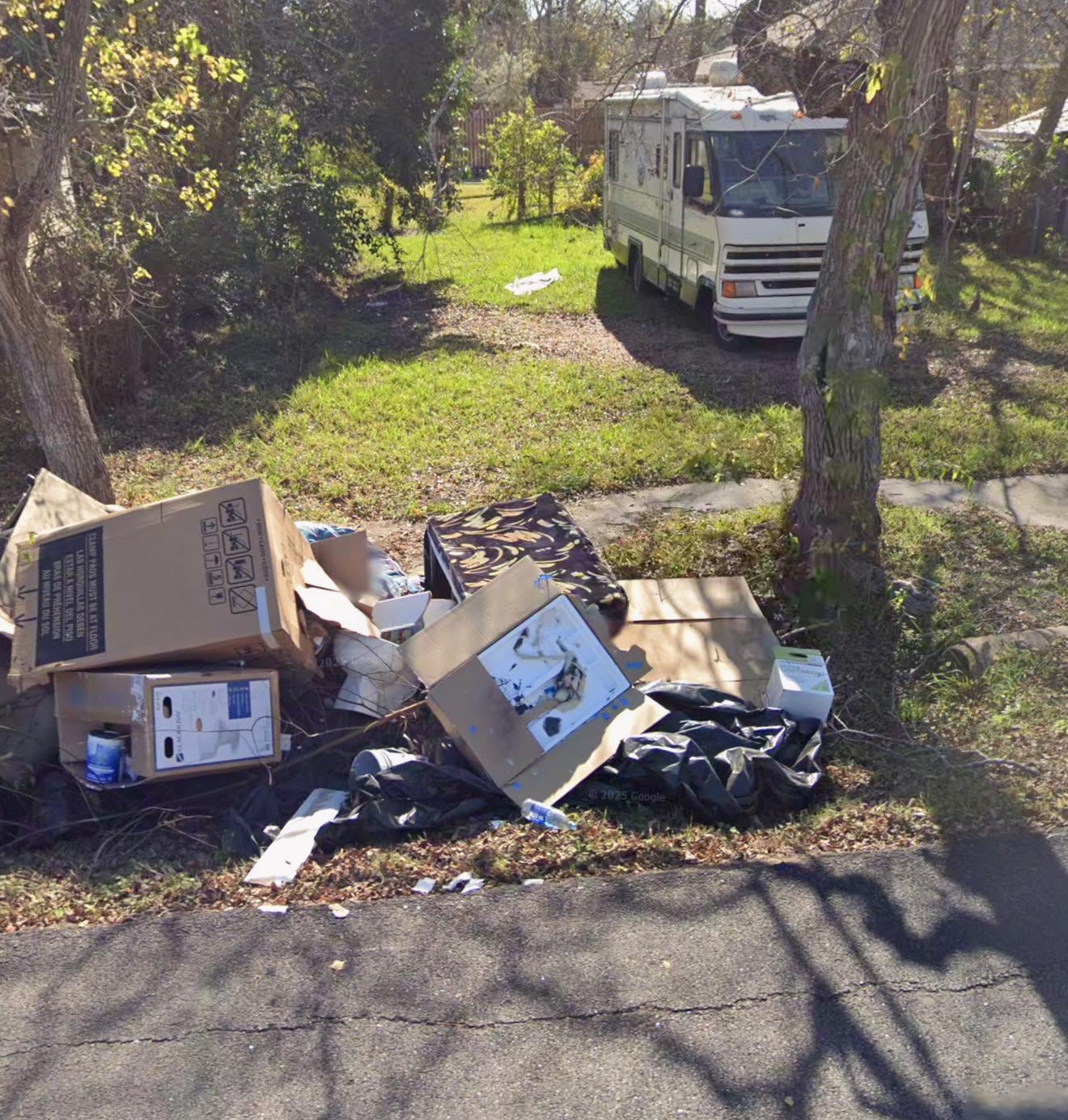 Trash pile across the street, broken down cars parked on the grass