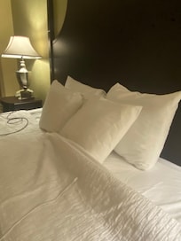 Four tiny pillows on king size bed, and not very white