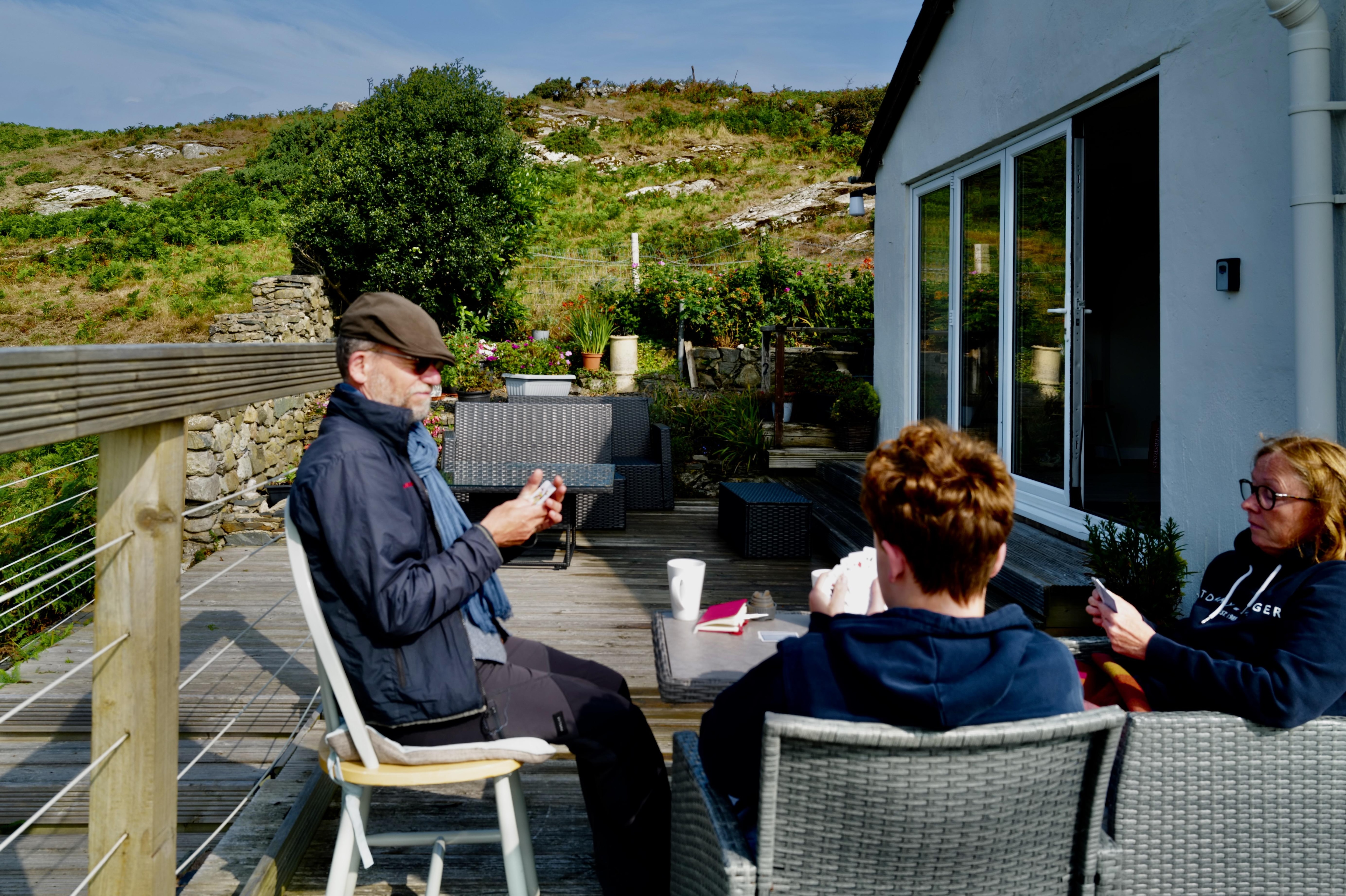 Sitting in front of the cottage playing cards