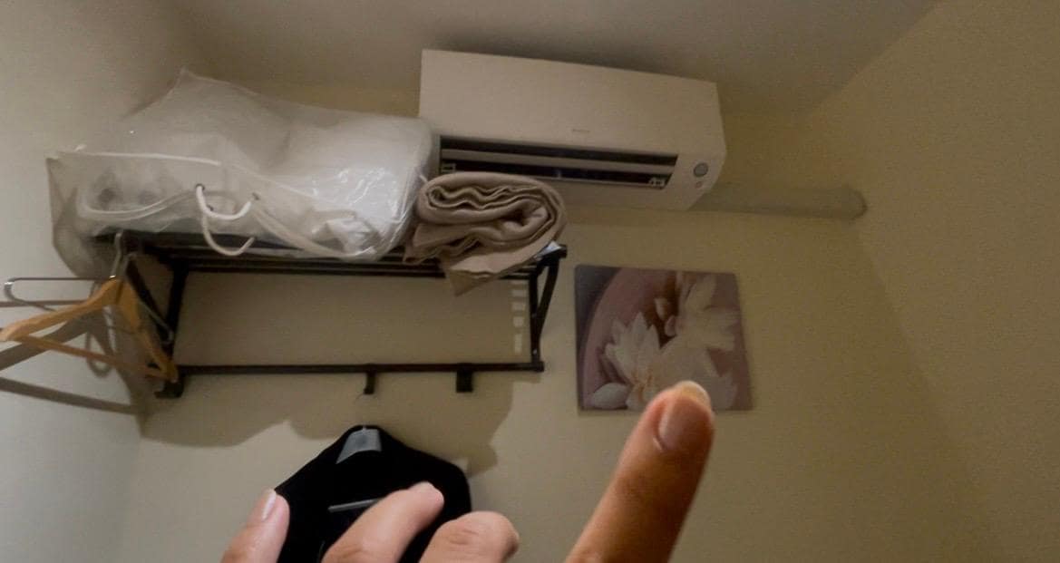 Em cima da cama tinha o ar condicionado, cabideiro, coberta extra..