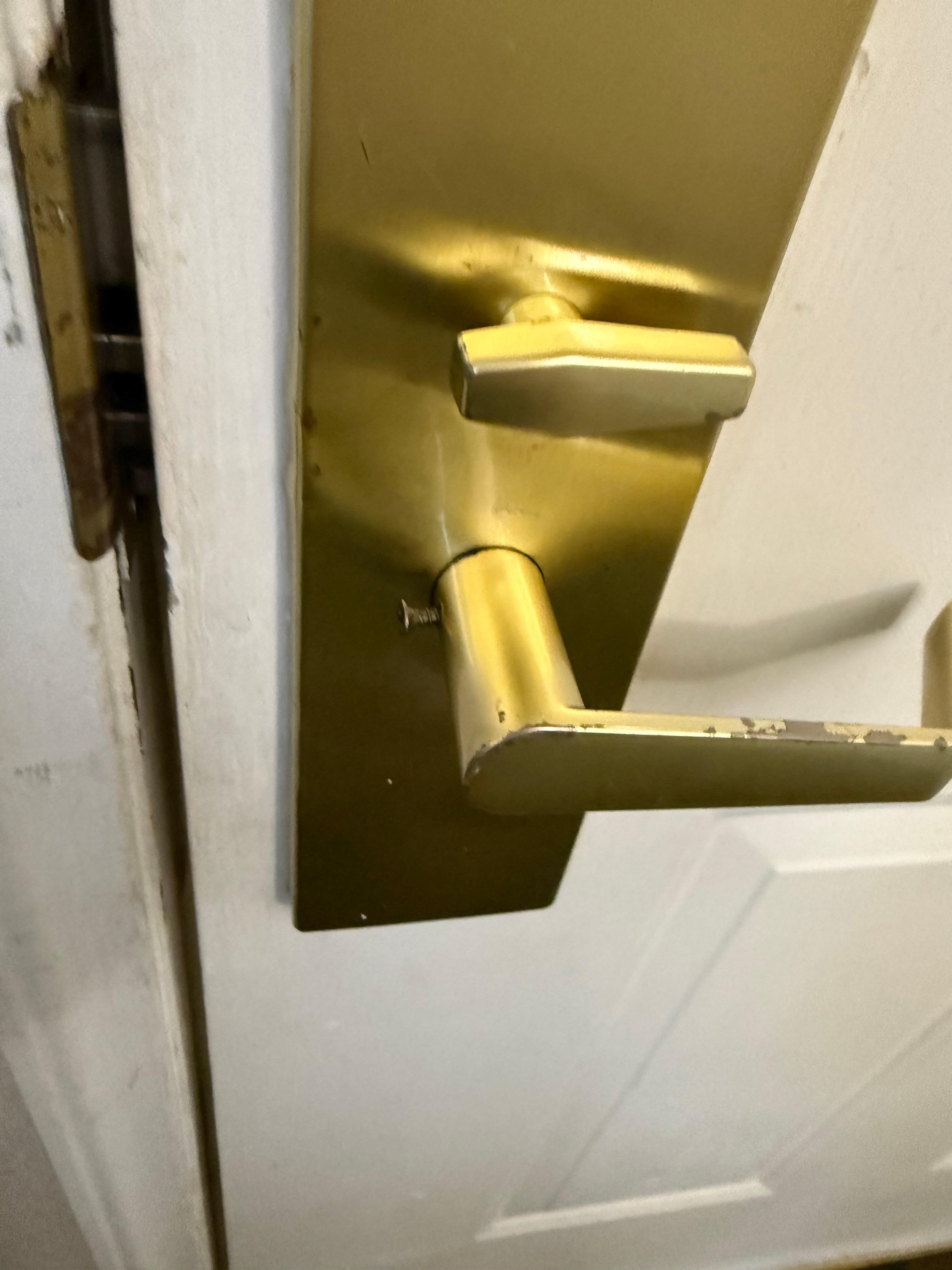 Long screw barely hanging the door knob onto the door.