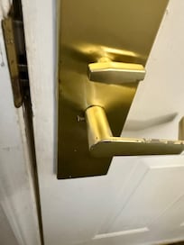 Long screw barely hanging the door knob onto the door.
