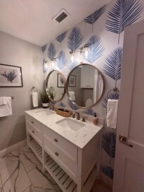 Guest bathroom featuring a double vanity and a tub/shower combo.