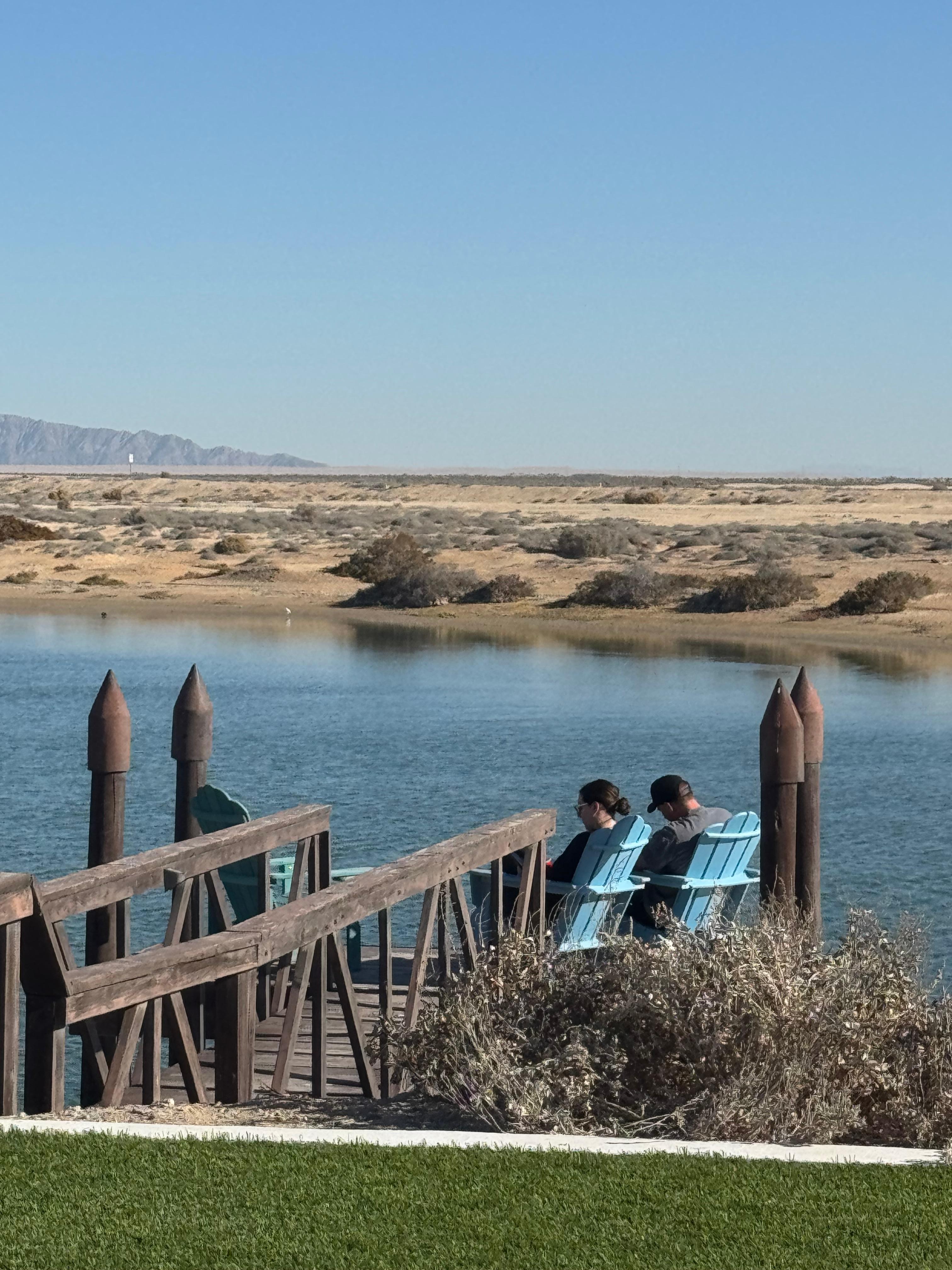 Pier over lagoon with Adirondack chairs.