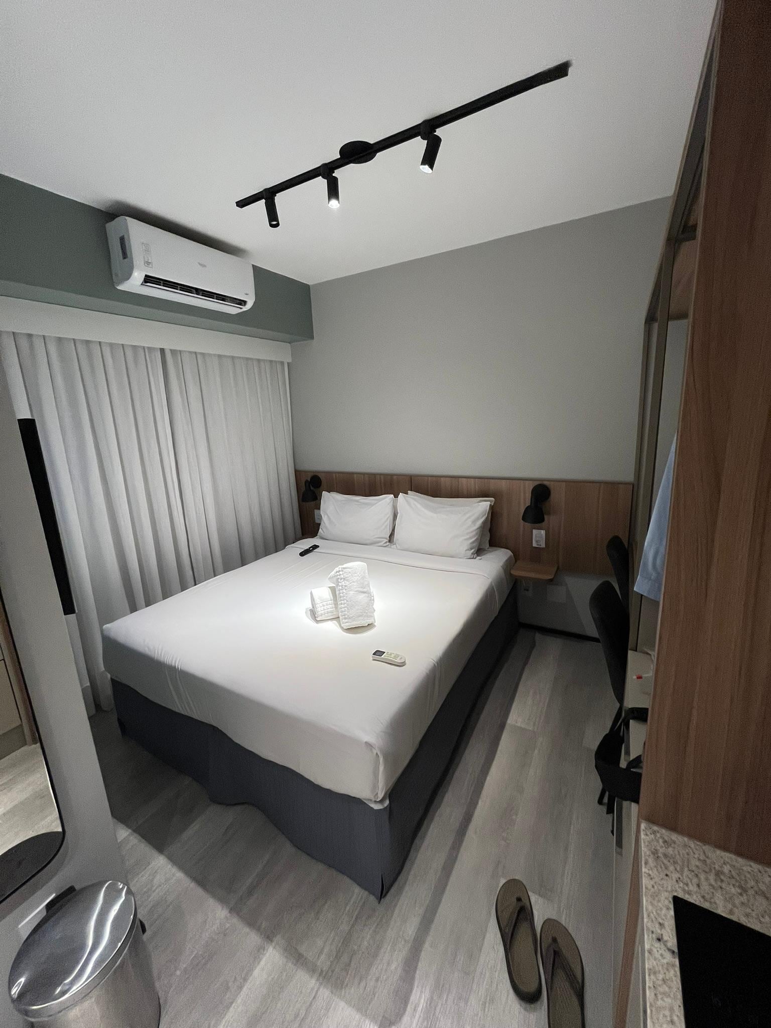 Cama de casal, do lado esquerdo porta de acesso à varanda que é fechada com cortina de vidro.